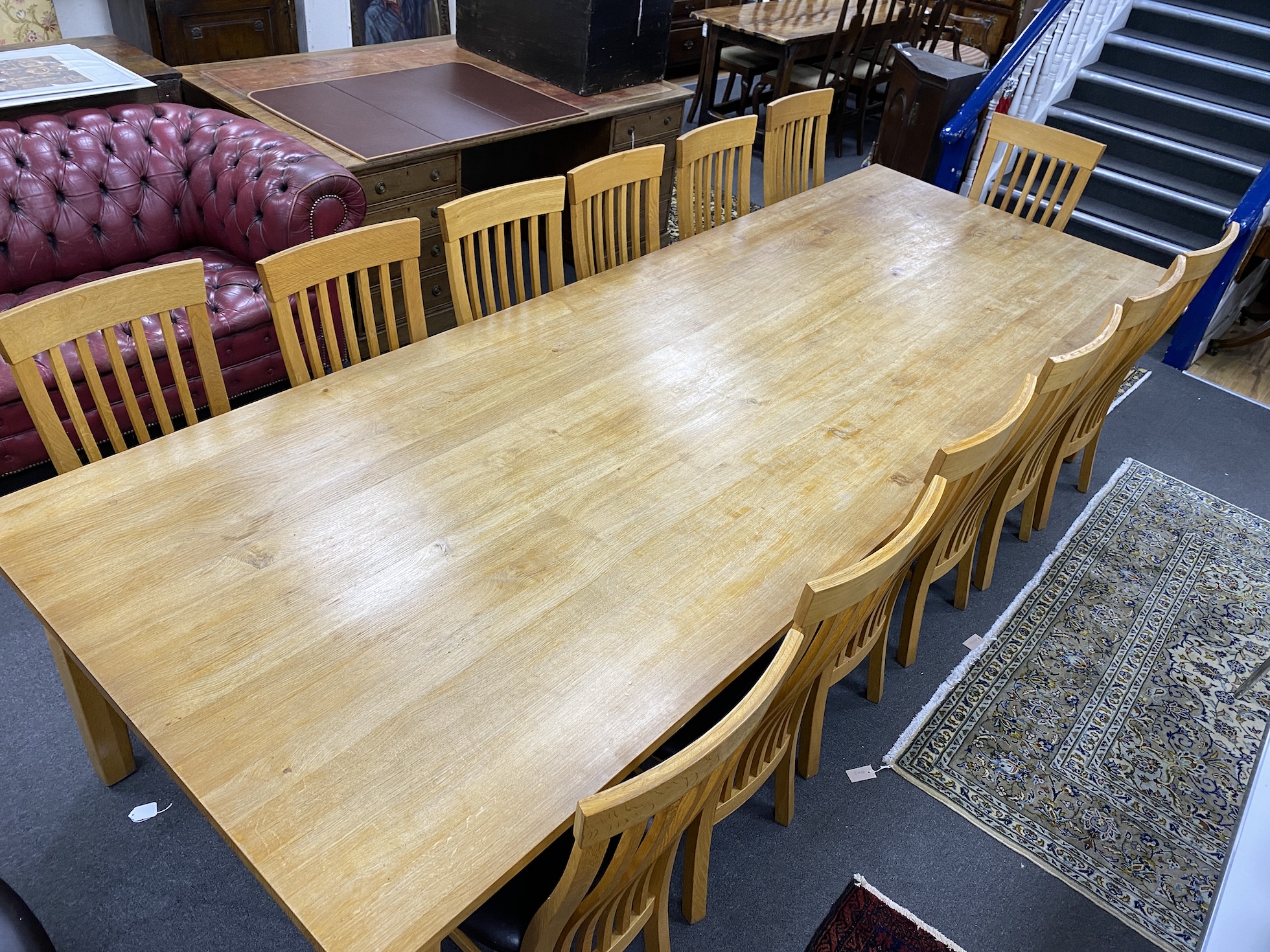 A large contemporary rectangular oak dining table, length 330cm, depth 119cm, height 76cm, and fourteen associated wavy bar back dining chairs.